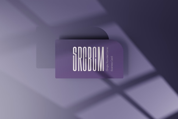 A minimalist card with rounded corners and the letters SRCBCM prominently displayed in large white font on a purple background. Below it, smaller text reads 'Single Rounded Corner Business Card'. Shadows from a window create geometric patterns on the surface.