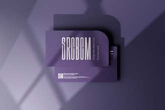 A business card mockup with a rounded corner design placed on a purple surface. The card features bold, modern typography with the text 'SRCBCM' prominently displayed. Light and shadow effects create a stylish and professional atmosphere.