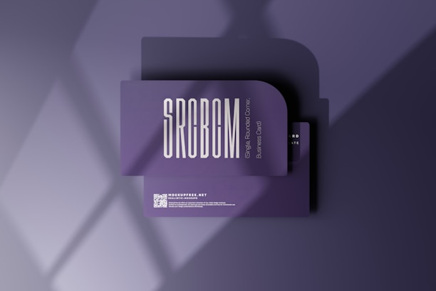 A business card mockup with a rounded corner design placed on a purple surface. The card features bold, modern typography with the text 'SRCBCM' prominently displayed. Light and shadow effects create a stylish and professional atmosphere.