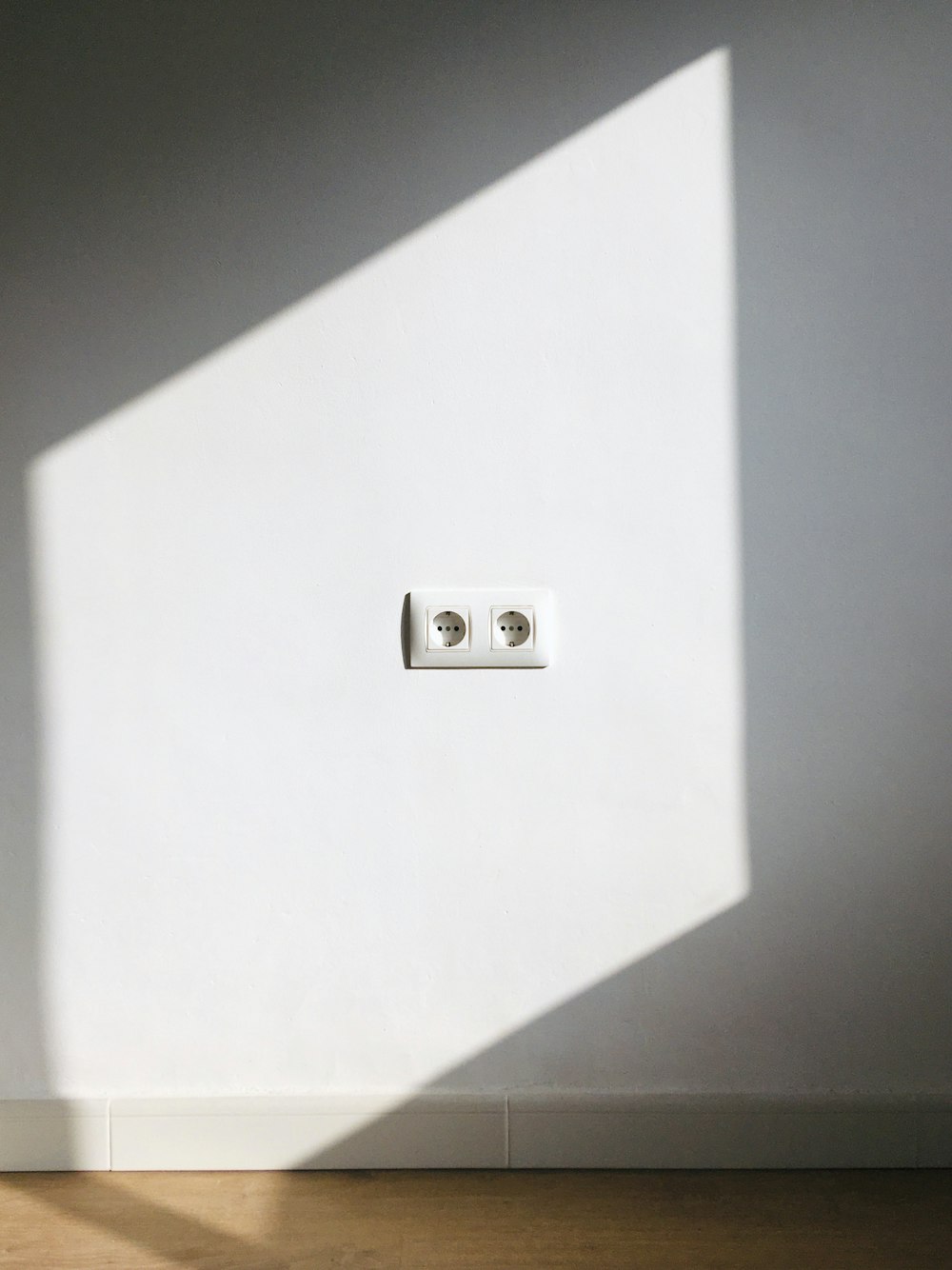 a light switch in a white room with a shadow on the wall