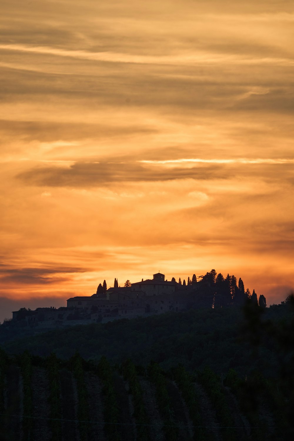 a sunset view of a castle on top of a hill