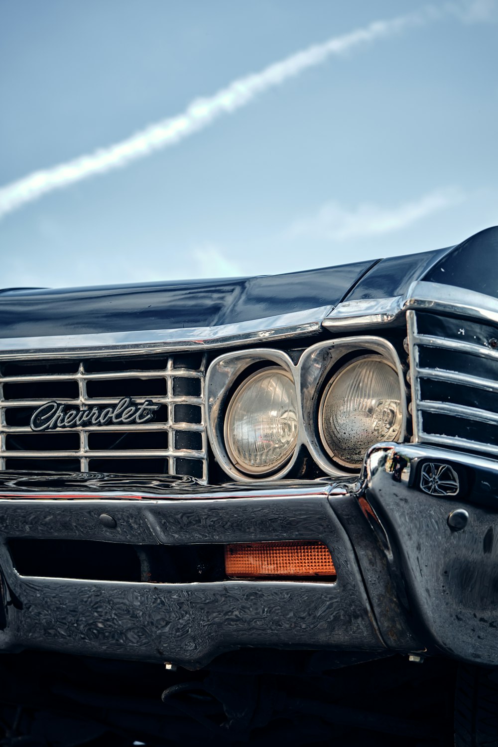 an old black car with a smoke trail in the background