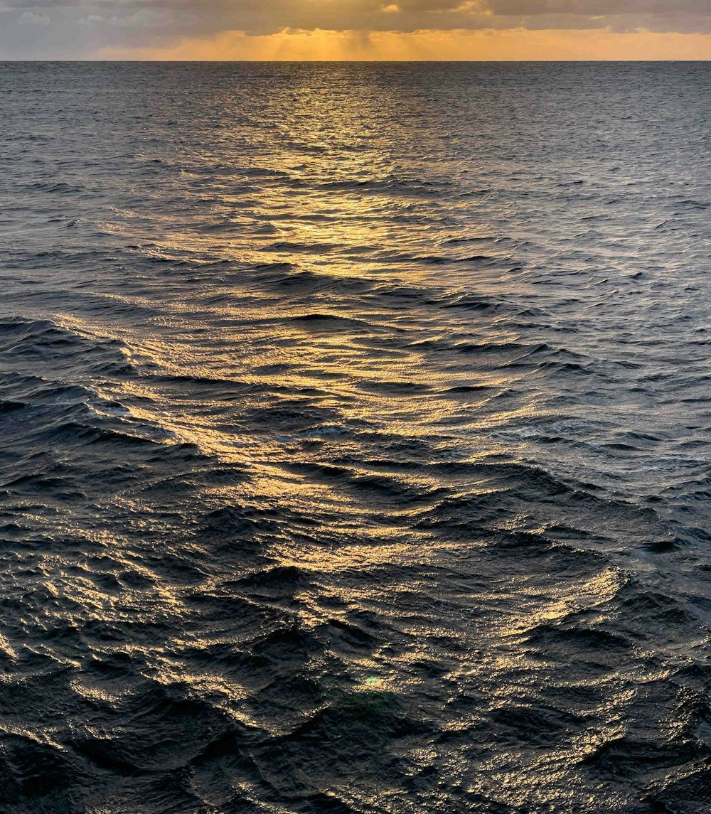 a large body of water with a sunset in the background