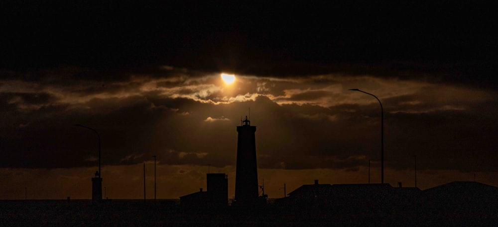 the sun is setting behind a tower in the sky