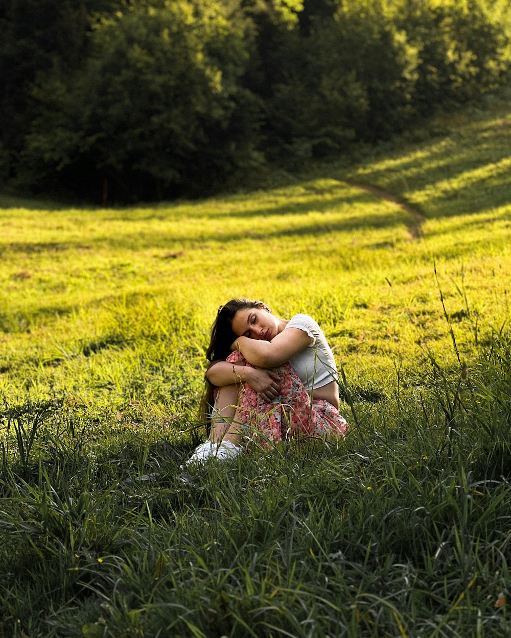 a woman sitting in the grass with her eyes closed