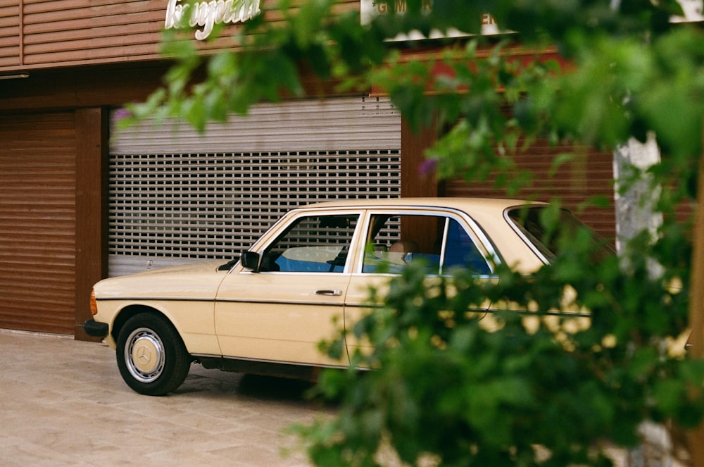 a beige car parked in front of a garage