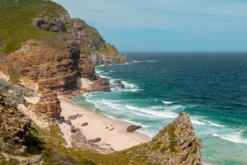 a sandy beach next to a rocky cliff