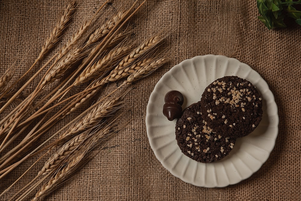 a plate with two cookies on it next to some ears of wheat