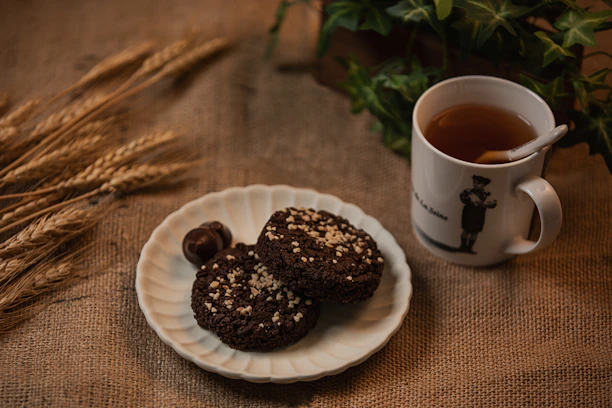 A cozy kitchen scene with a plate of oatmeal cookies next to a cup of tea on a wooden table.