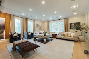 Elegant living room with plush neutral sofas, soft taupe walls, and dark accent lighting creating a warm ambiance