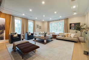 Spacious living room with charcoal black accents and light beige furnishings, bathed in natural light.