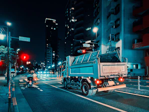 Nighttime shot of a sleek tow truck with glowing LED lights operating on a city street.