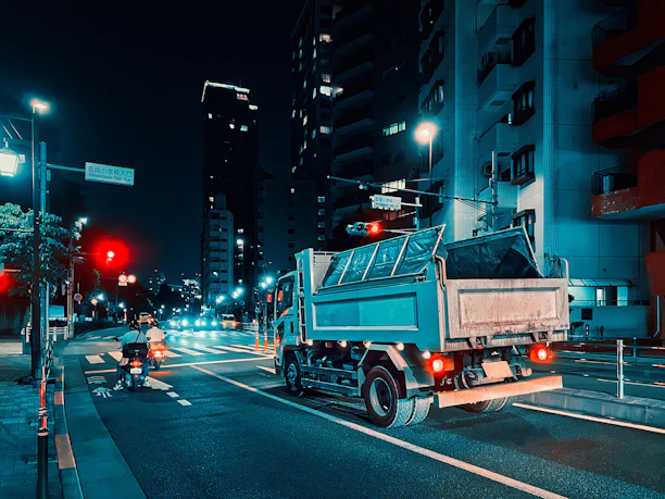 Nighttime shot of a sleek tow truck with glowing LED lights operating on a city street.