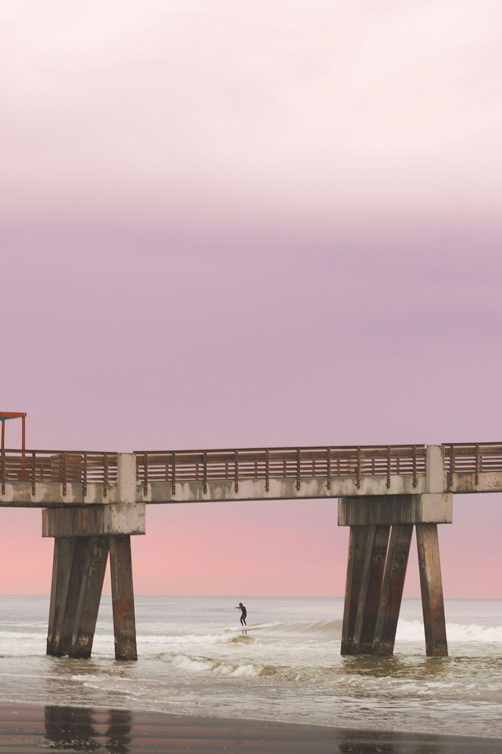 a person standing on a surfboard under a bridge