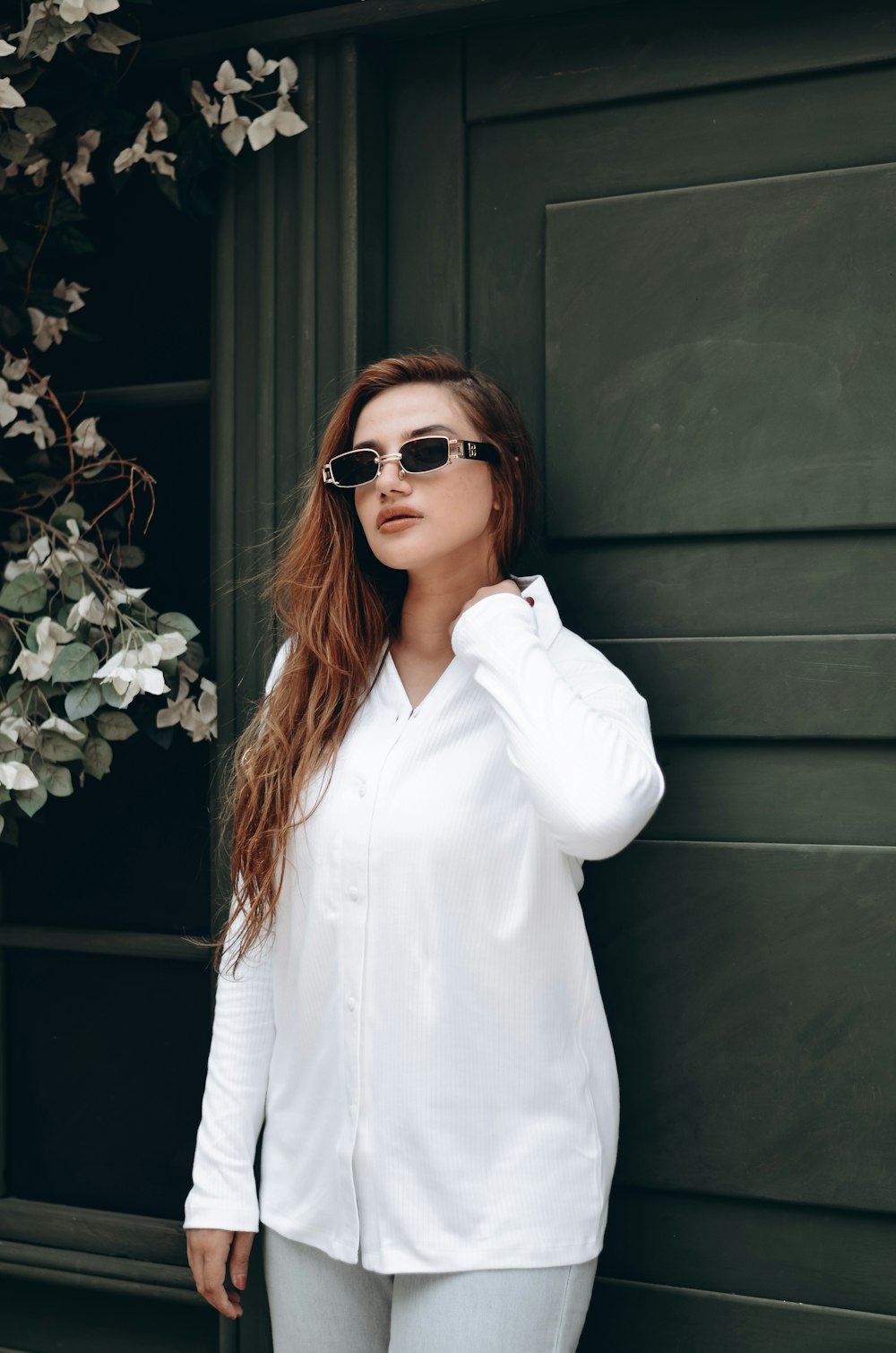 a woman wearing sunglasses leaning against a wall