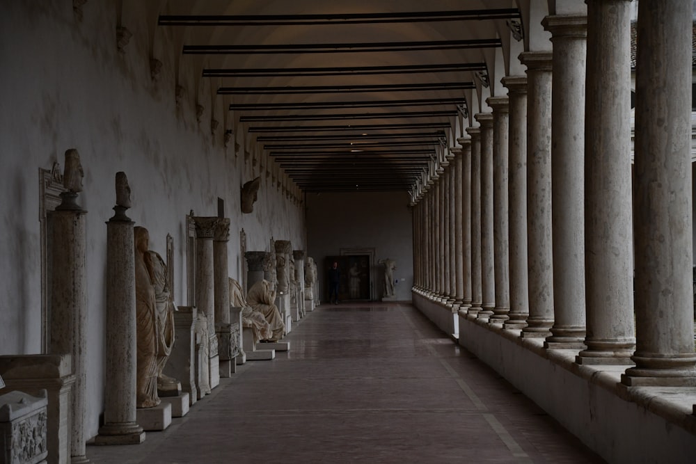 um longo corredor forrado de colunas e estátuas