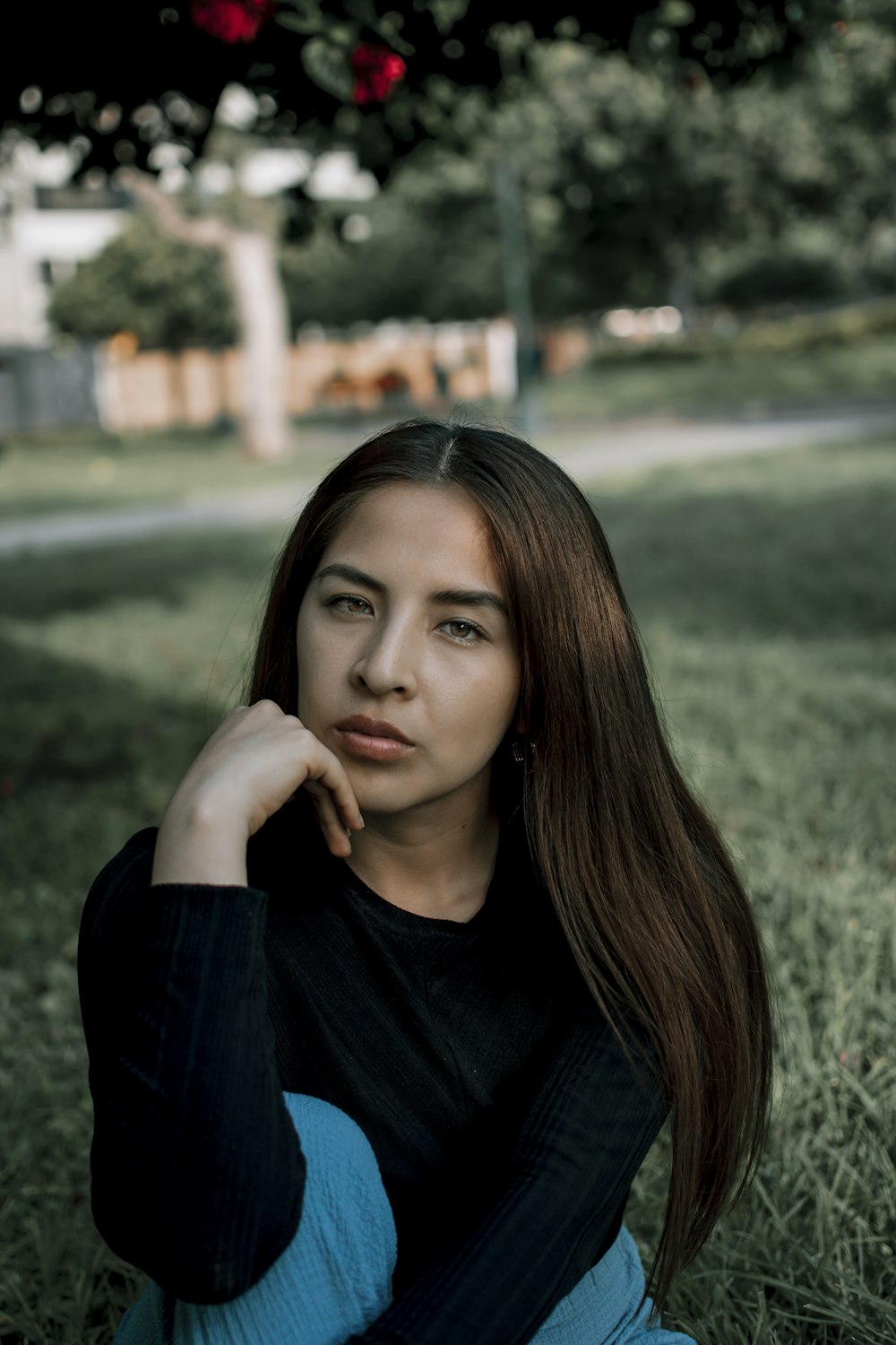 a woman sitting in the grass with her hand on her chin