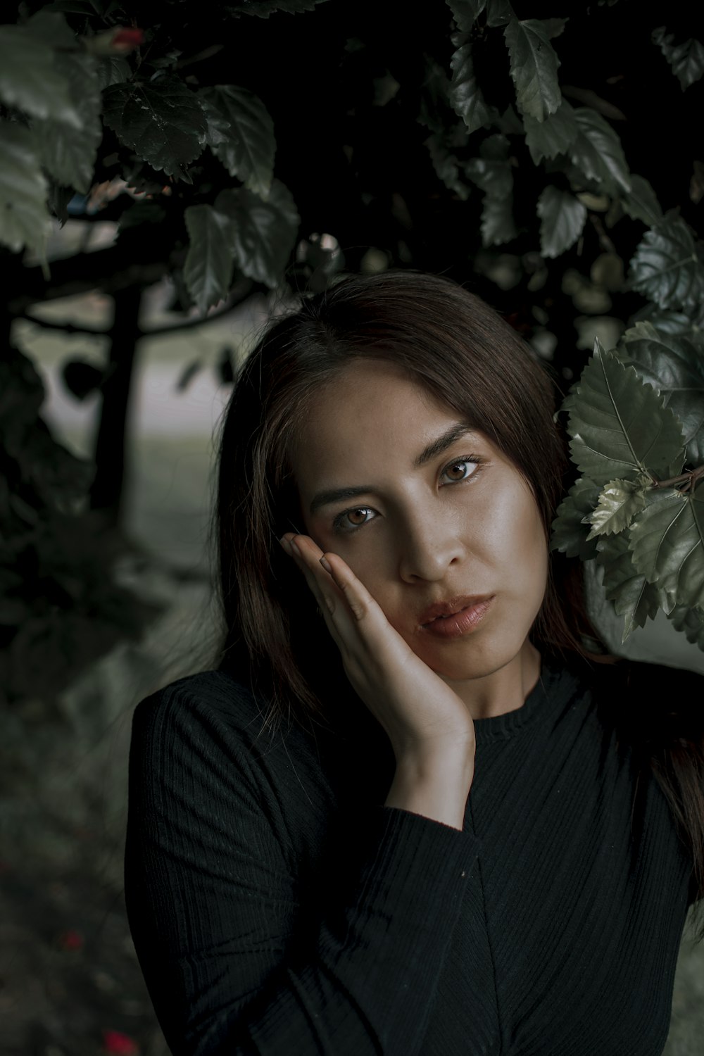 a woman standing under a tree with her hand on her face