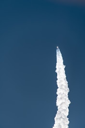 A sleek rocket taking off against a vibrant blue sky, symbolizing growth and ambition.