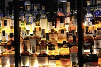Elegant display of premium whiskey bottles on a polished wooden shelf under soft lighting