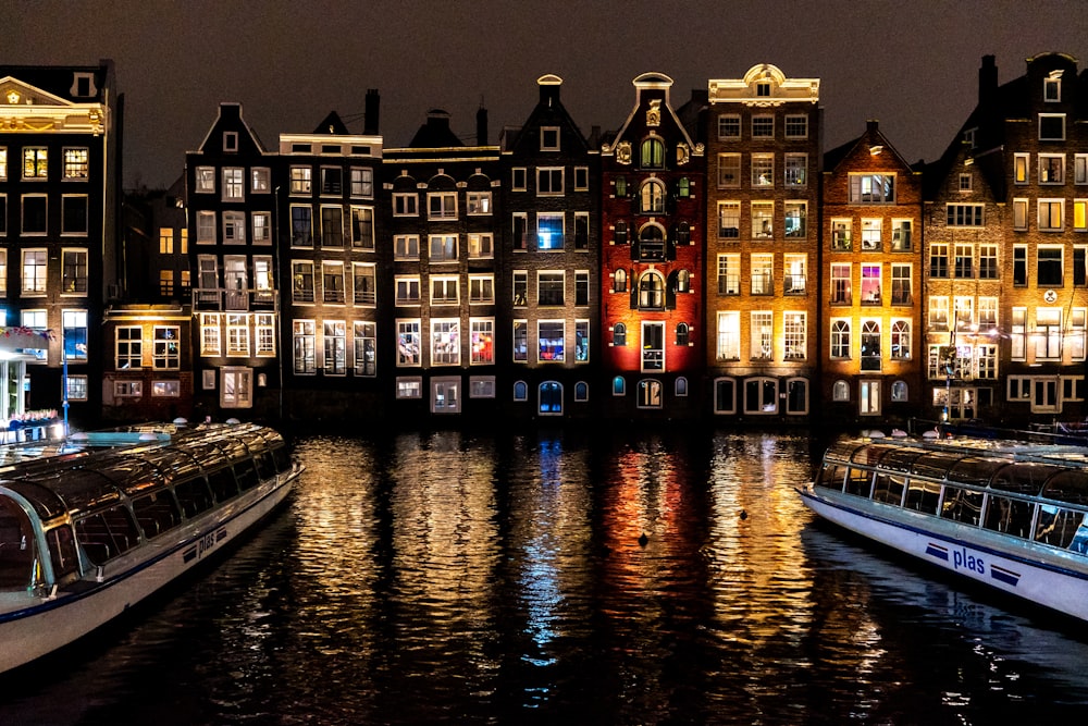 a group of boats floating on top of a river next to tall buildings