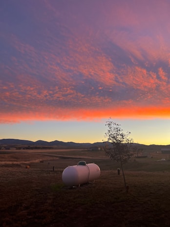 A serene landscape of a Midwest farm with a propane tank in the foreground.