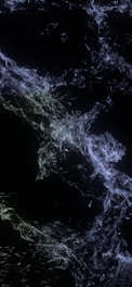 Suspended, interconnected strands of blue and white particles create an abstract, web-like pattern against a dark background, resembling cosmic or neural structures.