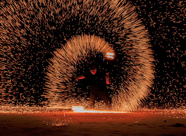 A magical fire performance illuminating a night festival with warm glowing embers