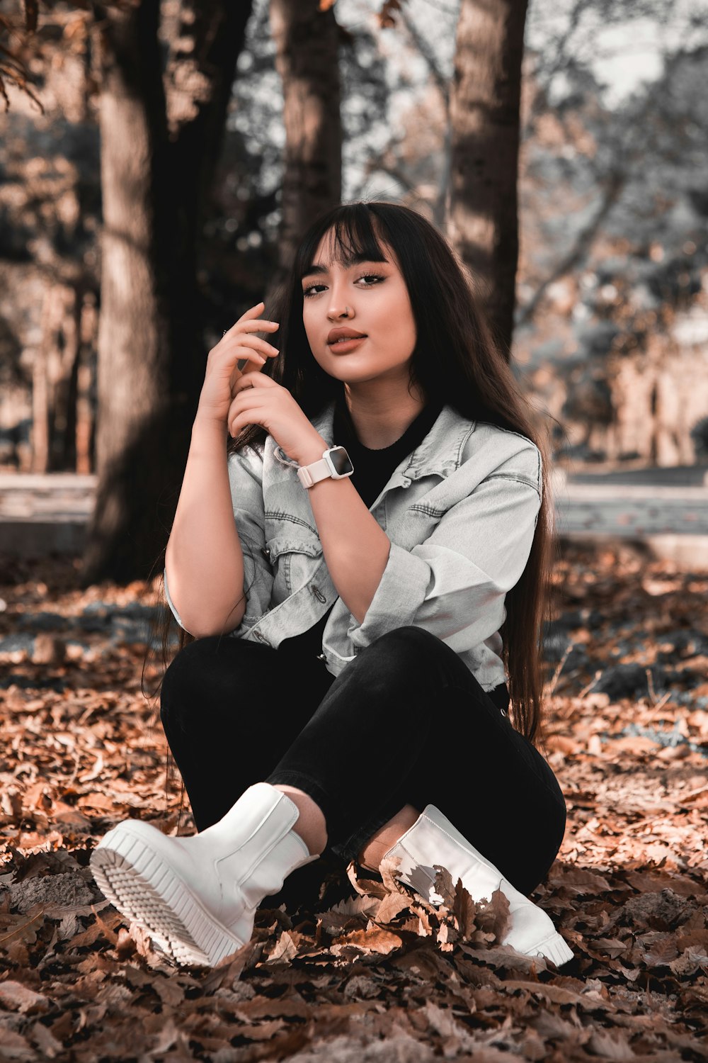 a woman sitting on the ground surrounded by leaves