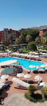 A vibrant resort pool area with happy guests enjoying sunny weather.