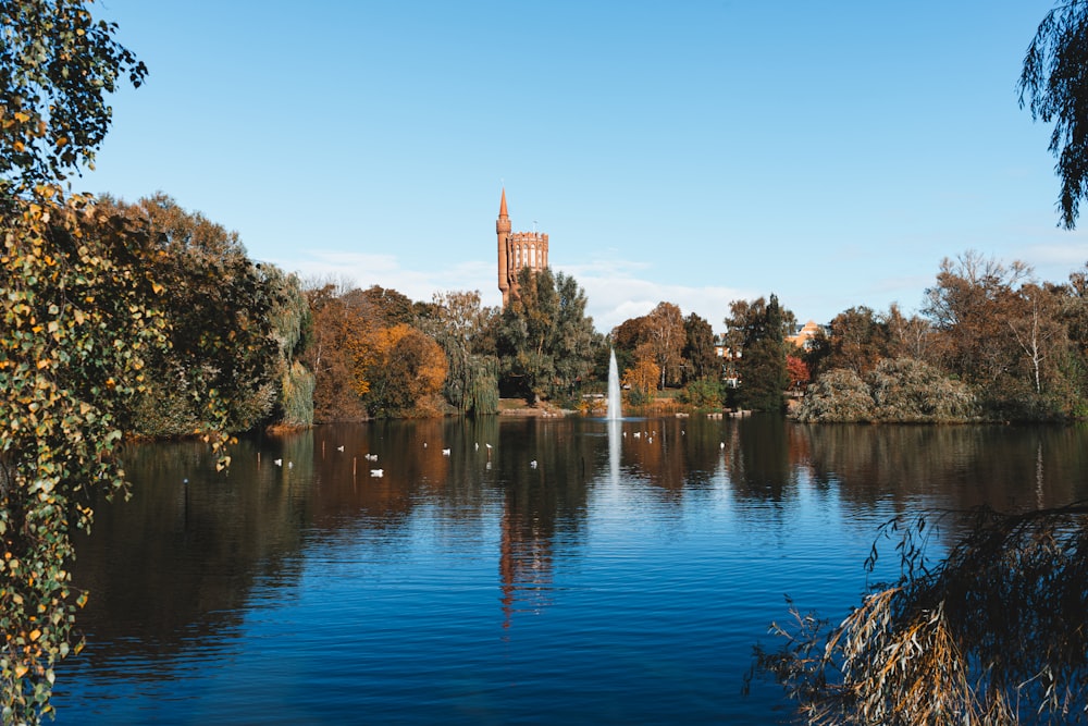 a lake surrounded by trees with a tower in the background
