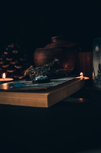 A dark, elegant mystical workspace with candles, crystals, and an open ancient book.