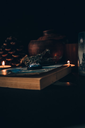 A dark, elegant mystical workspace with candles, crystals, and an open ancient book.