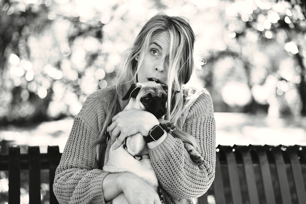 a woman sitting on a bench holding a dog