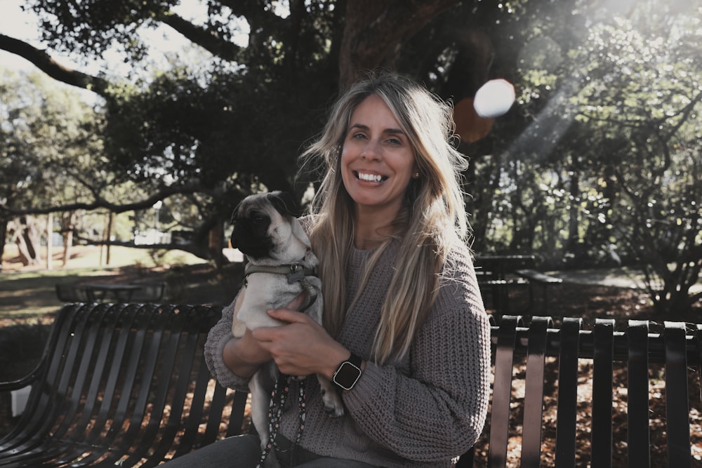 a woman sitting on a bench holding a dog