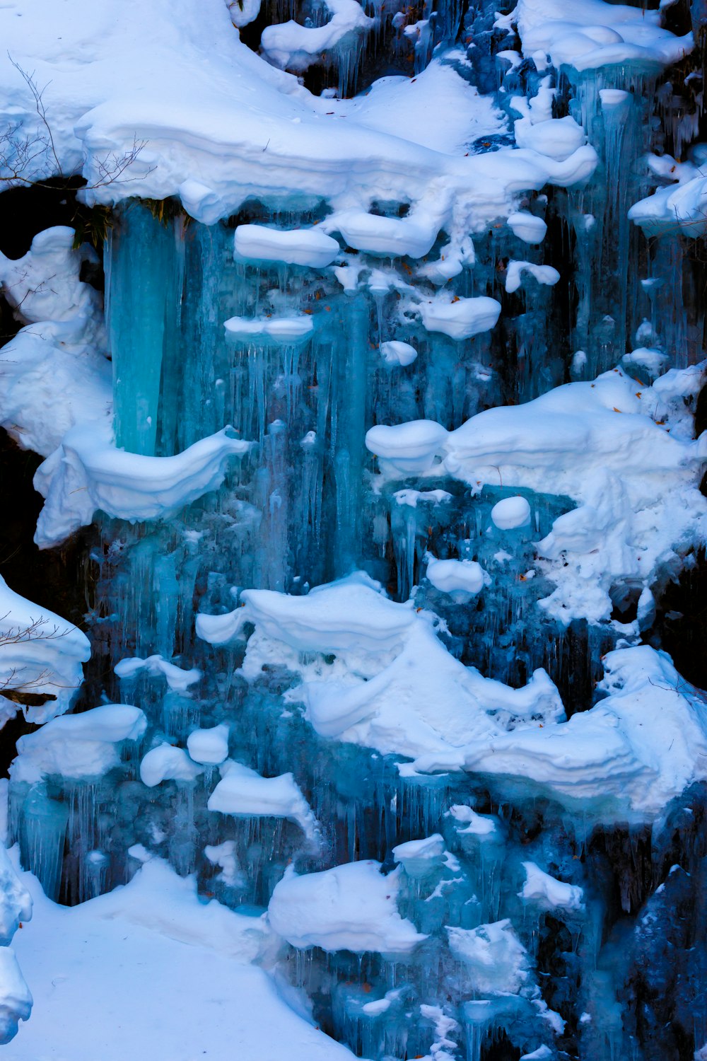 a waterfall covered in ice and snow next to a forest