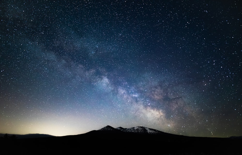 the night sky with stars above a mountain