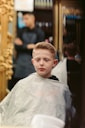 a young boy getting his hair cut at a barber shop