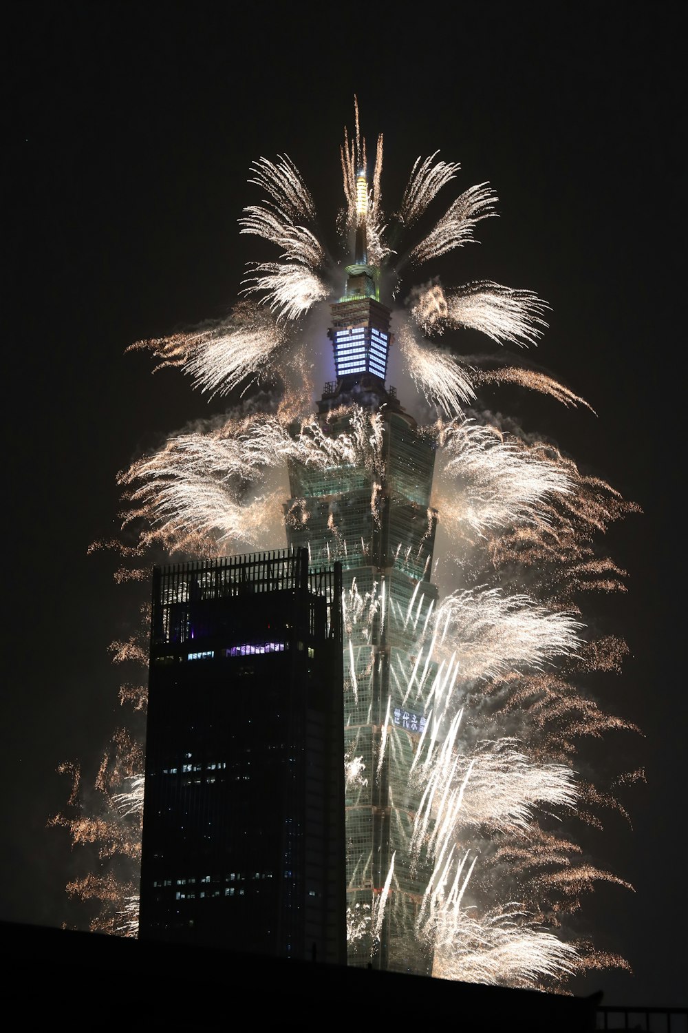 fireworks are lit up in the sky above a tall building