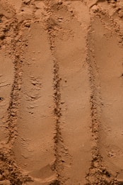 a close up of a sandy beach with tracks in the sand