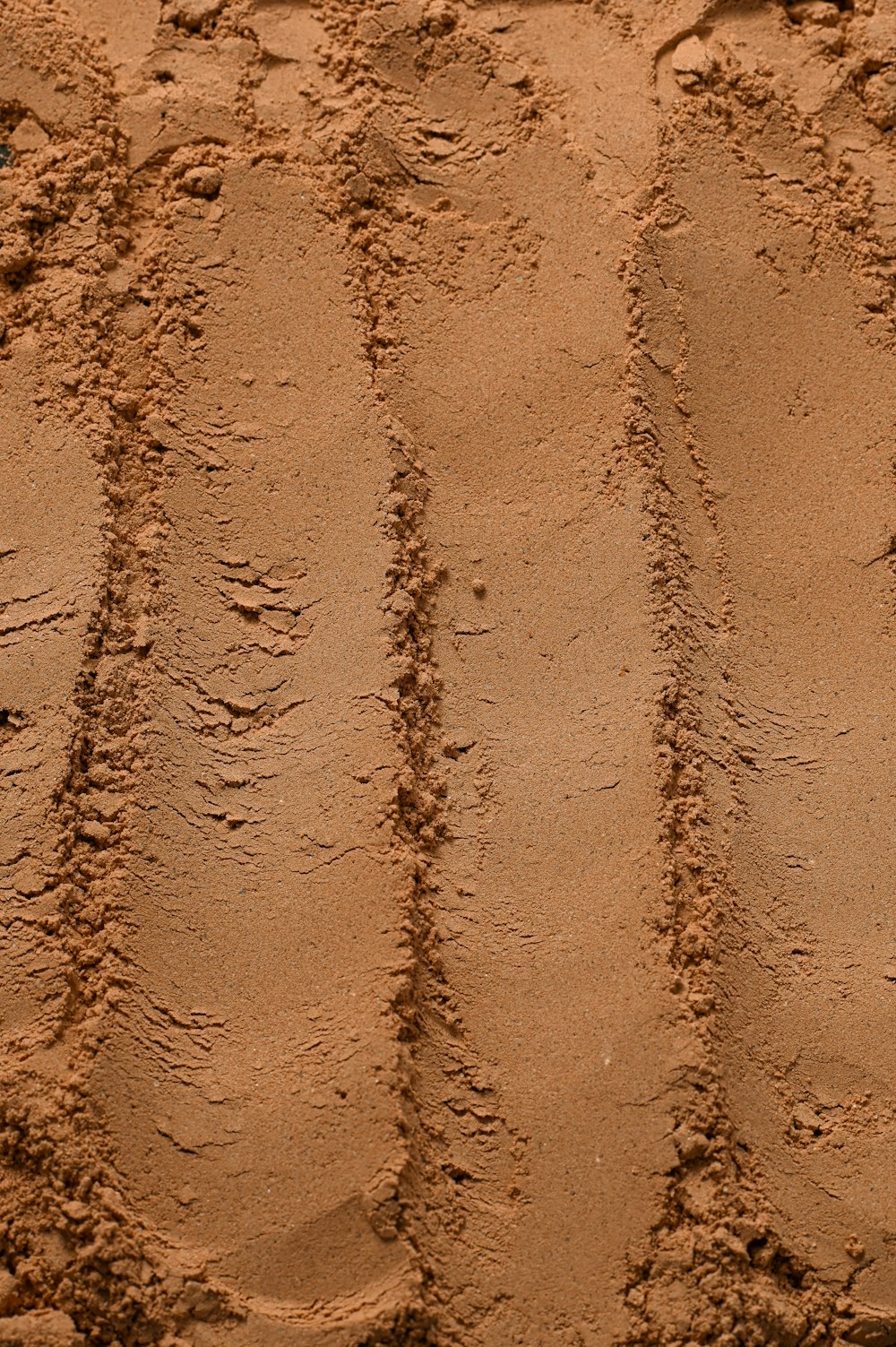 a close up of a sandy beach with tracks in the sand