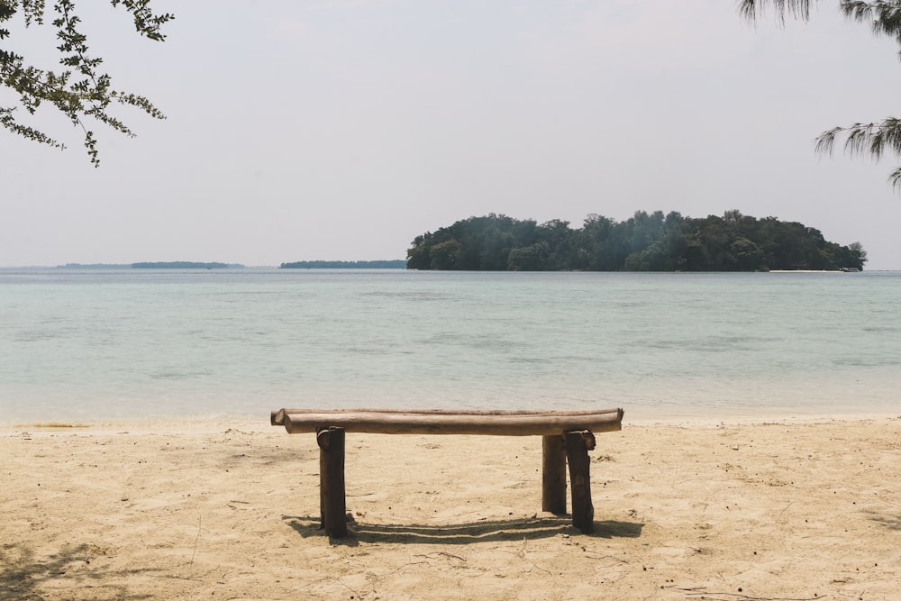 un banco de madera sentado en la parte superior de una playa de arena