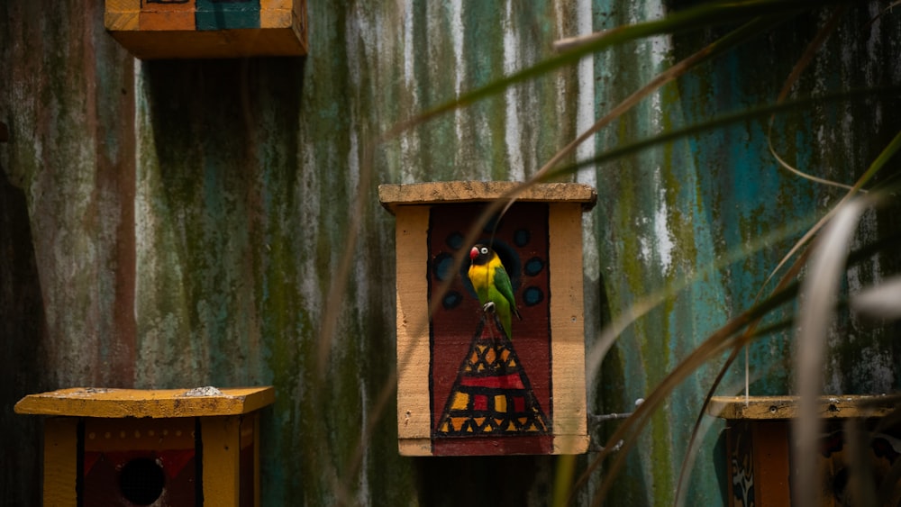a colorful birdhouse with a yellow and green bird perched on it's perch