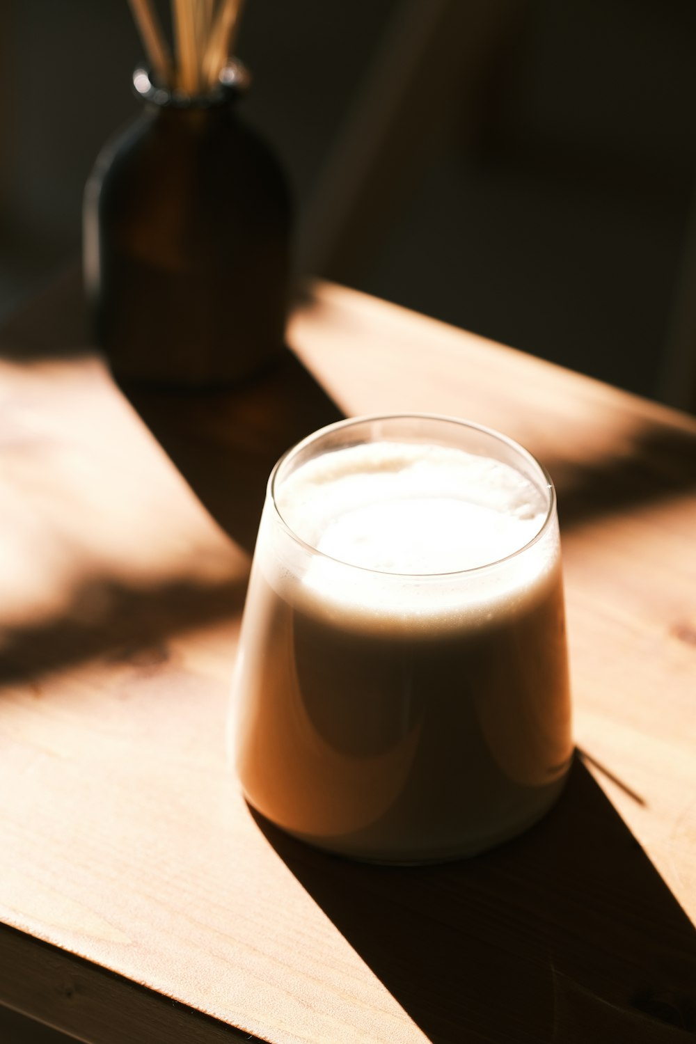 a glass of milk sitting on top of a wooden table