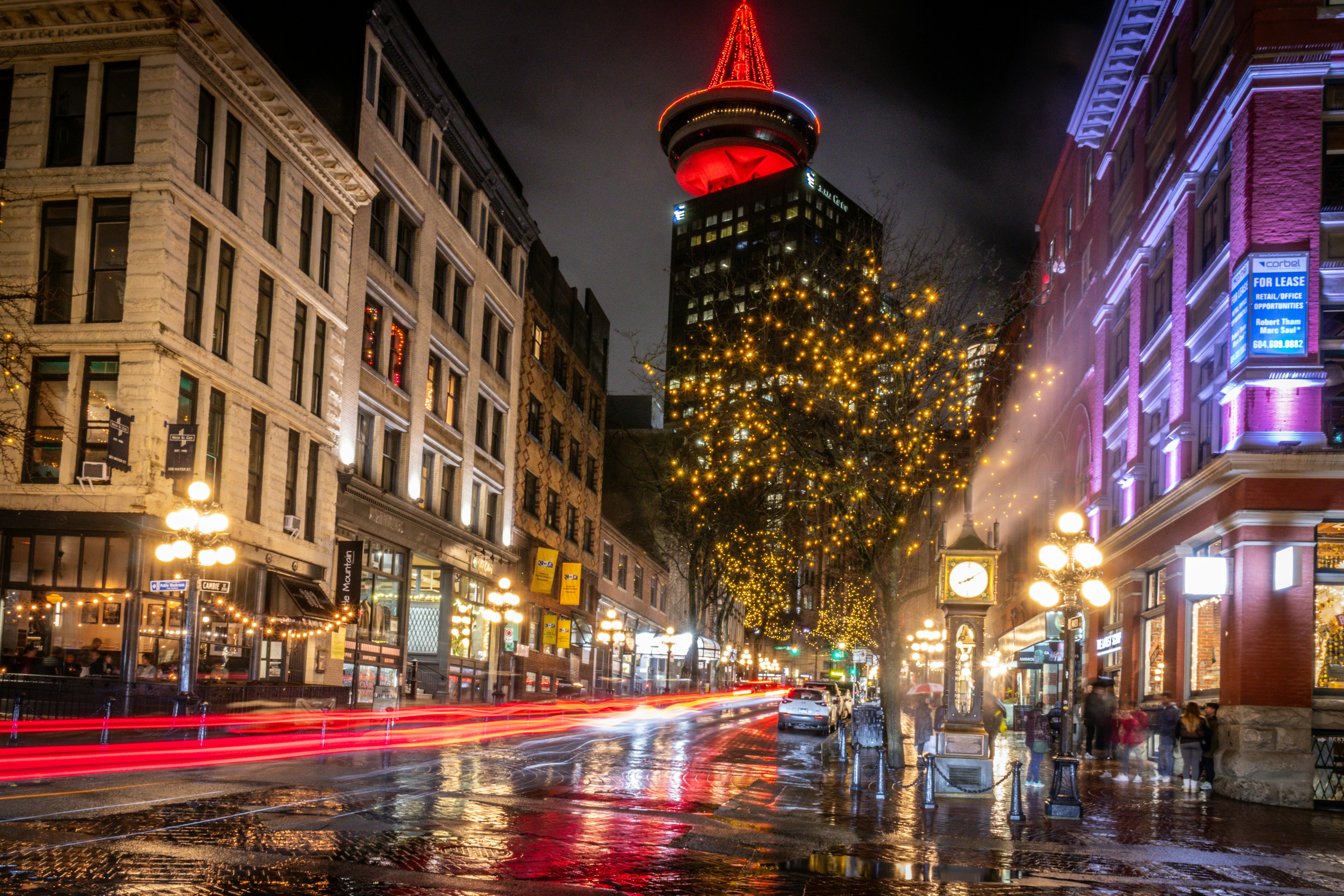 a city street at night with a christmas tree in the background