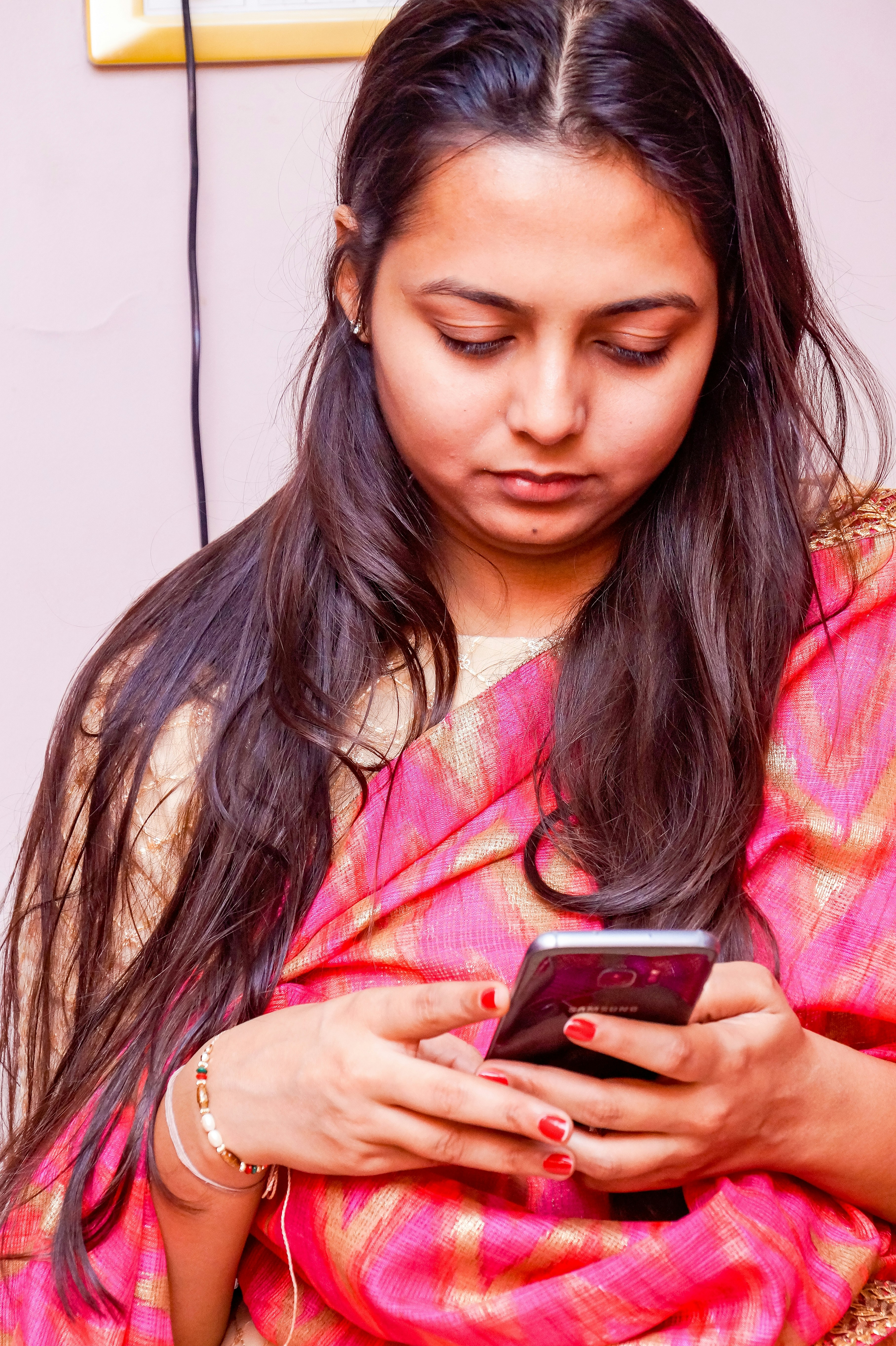 a woman in a pink sari using a cell phone