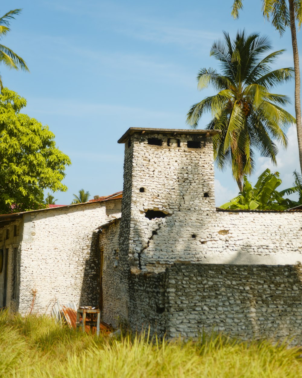 un vieux bâtiment en brique avec des palmiers en arrière-plan