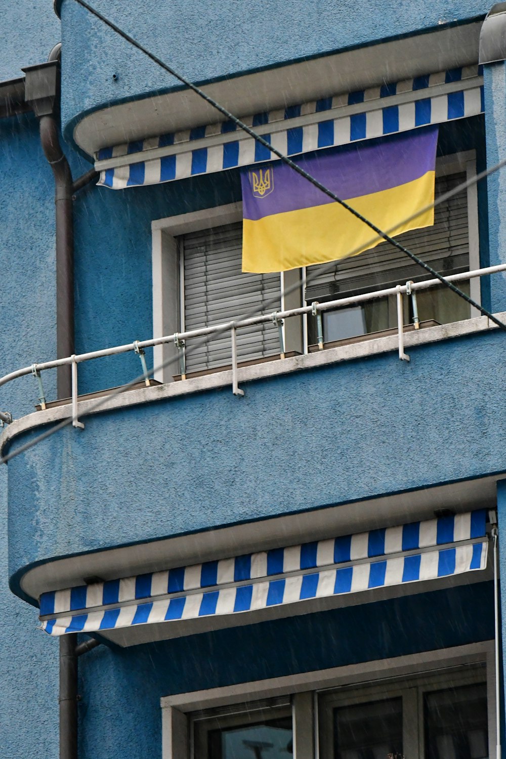 a blue building with a yellow and purple flag on the balcony