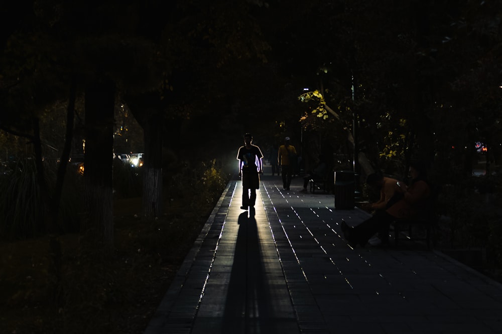 a person walking down a sidewalk at night