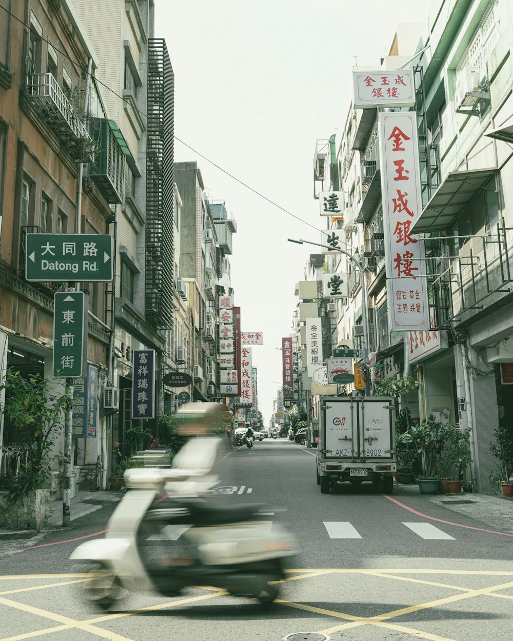 a scooter driving down a street next to tall buildings